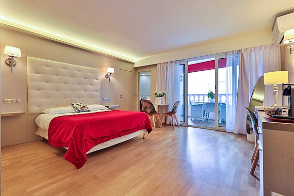 A hotel room with a red bed and a sliding glass door