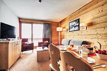 A living room with a couch and chairs and a tv