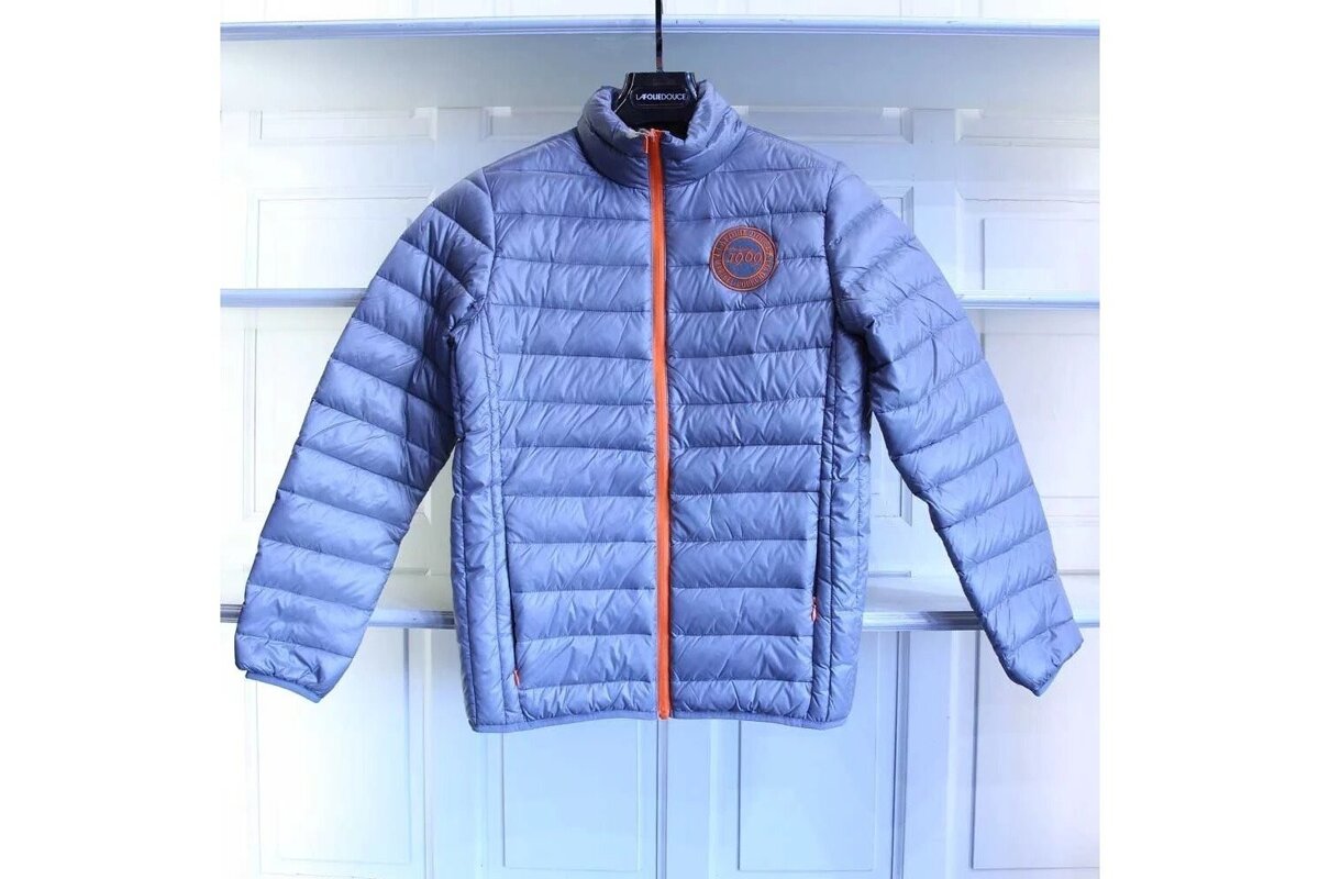 A grey padded jacket with an orange trim is hanging on a hanger