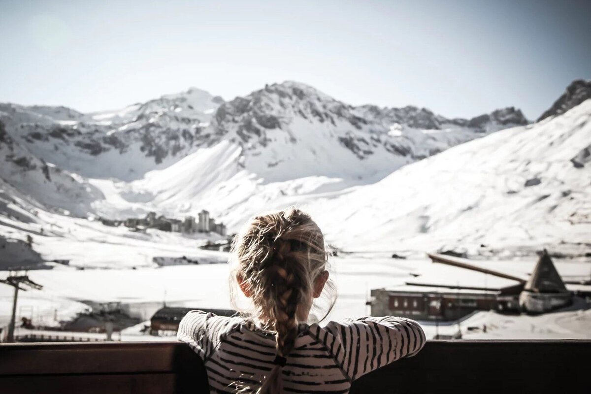 A woman looks out over a snowy mountain range