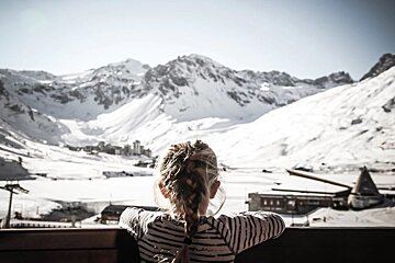 A woman looks out over a snowy mountain range