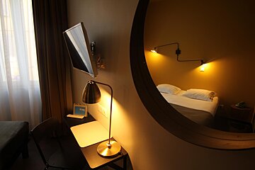 A hotel room with a reflection of a bed in a mirror