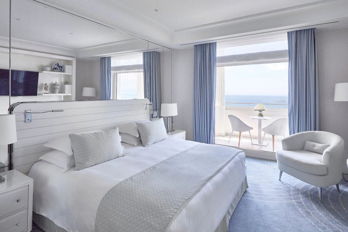 A bedroom with a large bed and a balcony overlooking the ocean
