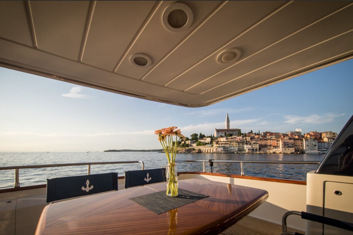 A table with a vase of flowers on it in front of a body of water