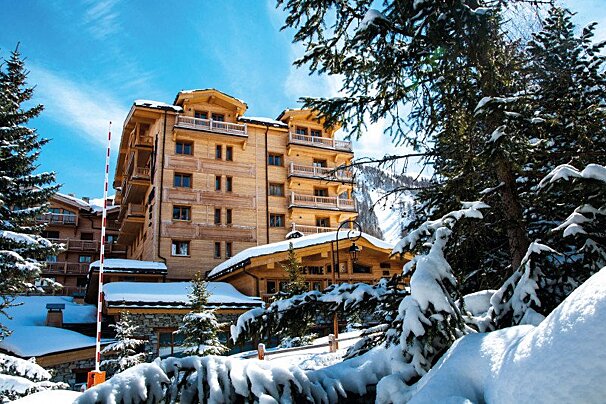 A large wooden building is surrounded by snow covered trees