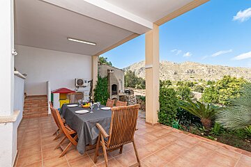 A table and chairs on a patio with mountains in the background