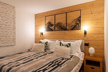 A bedroom with a wooden wall and a bed