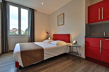 A bedroom with a single bed and red cabinets
