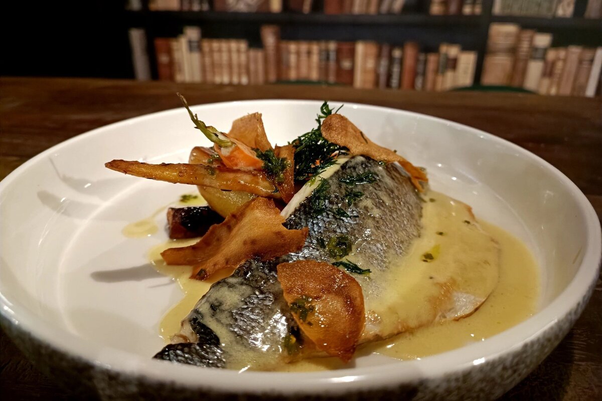 A white plate with a fish and vegetables on it
