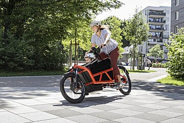 A woman is riding a bike with a baby in the back