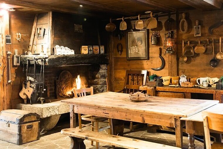 A room with a table and chairs and a fireplace with a picture of a man on the wall