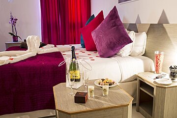 A hotel room with a bottle of champagne on the bed