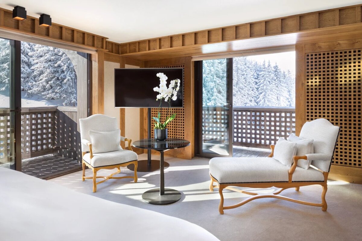 A room with two chairs a table and a flat screen tv