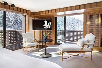 A room with two chairs a table and a flat screen tv