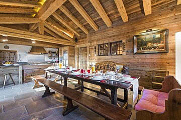 A wooden dining room with a long table and benches