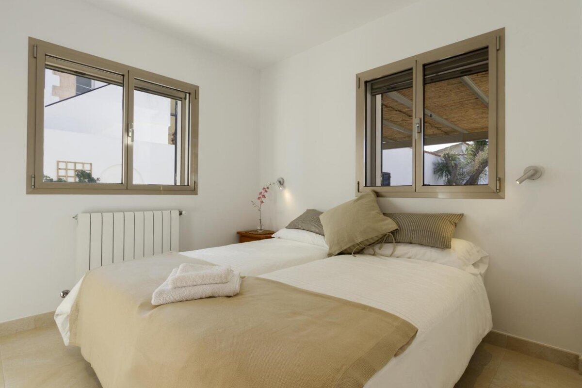 A bedroom with two beds and two windows