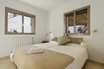 A bedroom with two beds and two windows