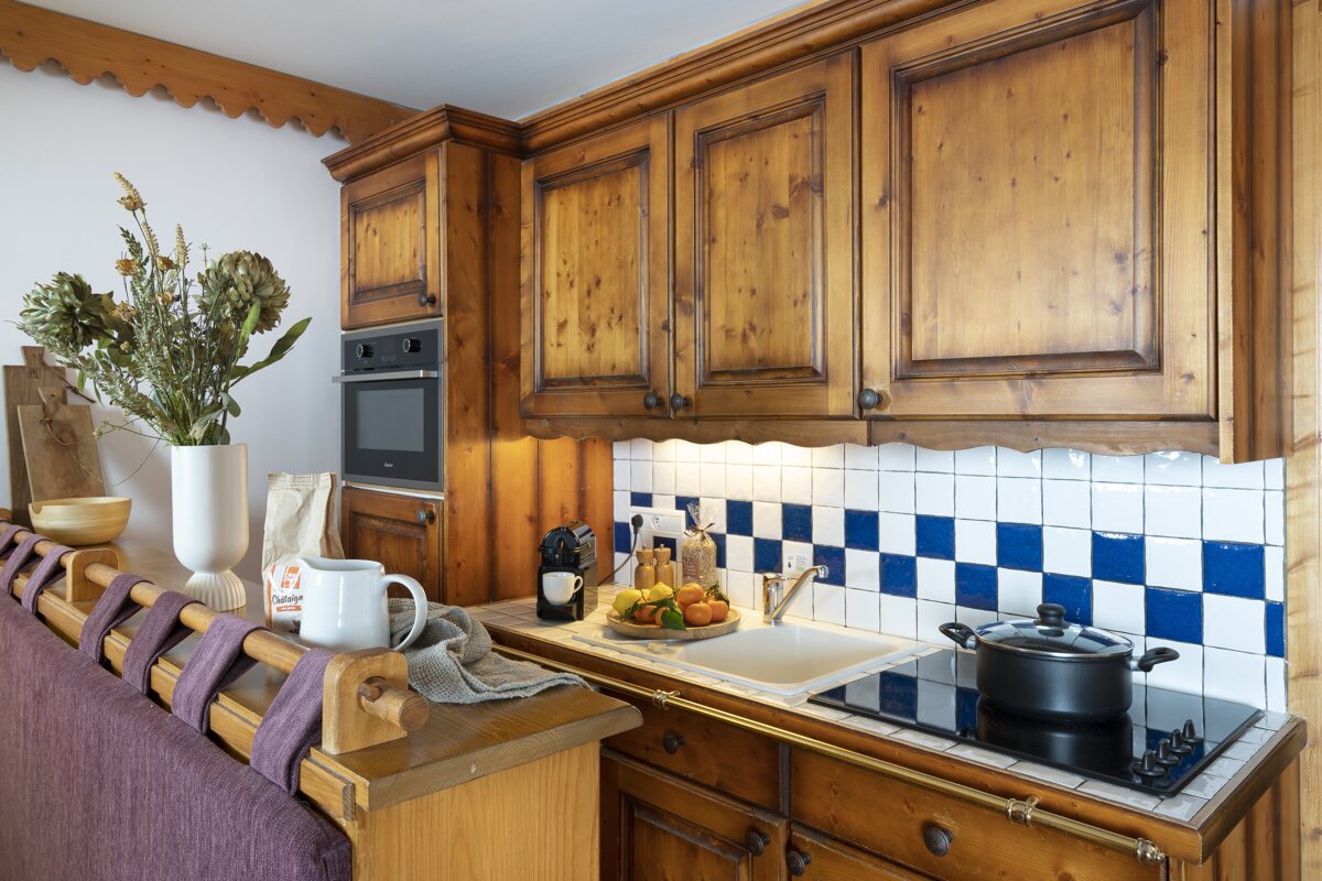 A kitchen with wooden cabinets and blue and white tiles