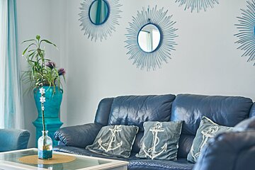 A blue leather couch with anchor pillows on it