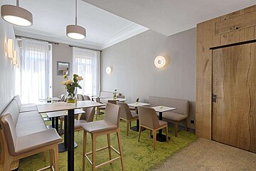 A room with tables and chairs and a green rug