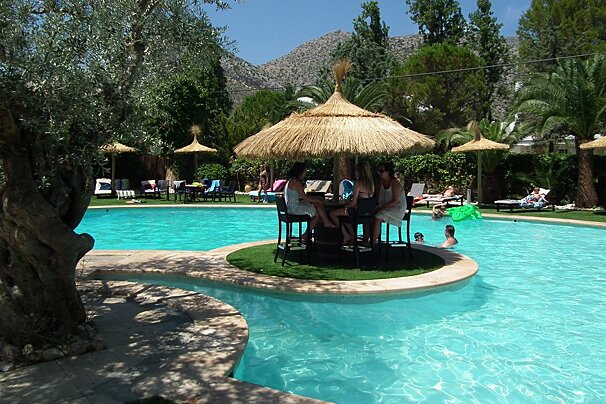 A group of people sit at a bar in the middle of a swimming pool