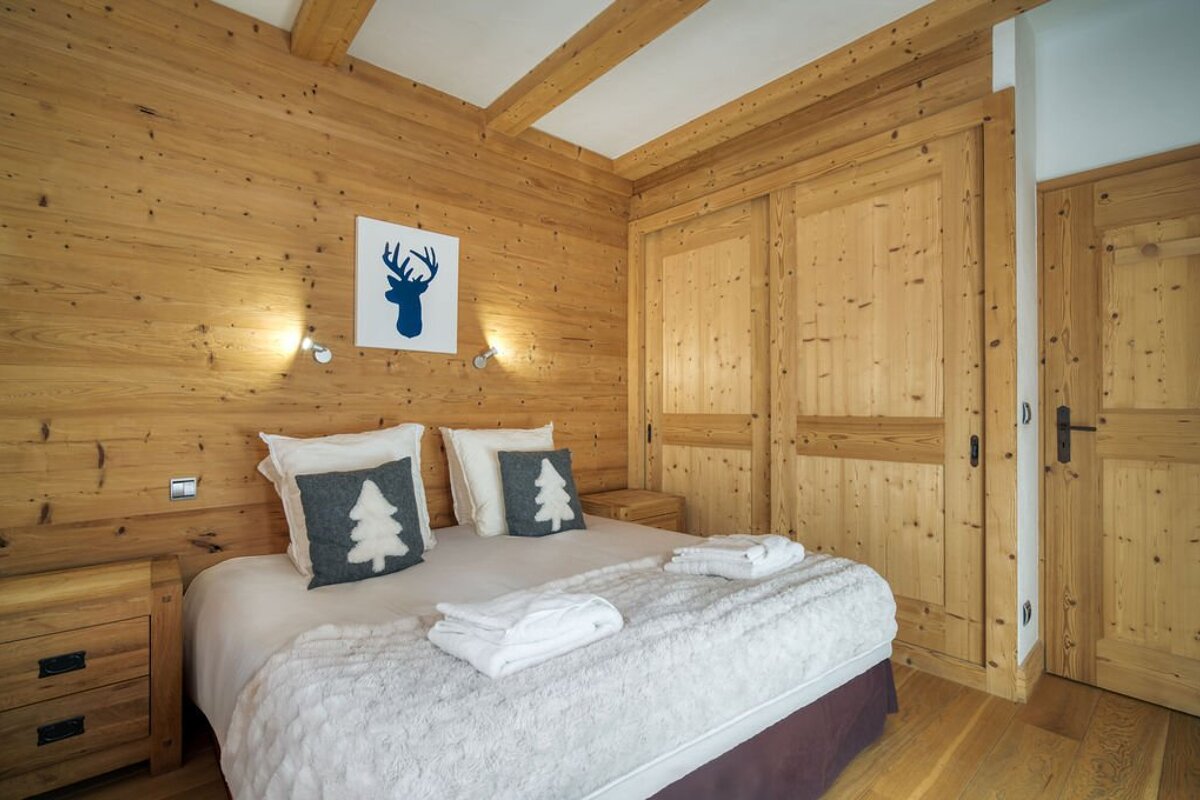 A bedroom with a deer head and trees pillows