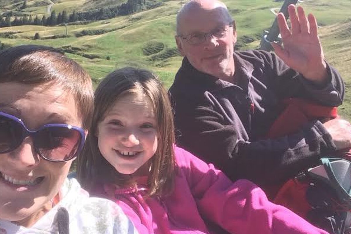 three people on a chair lift waving at the camera