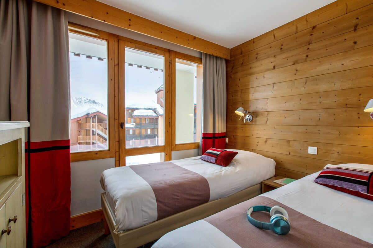 A bedroom with two beds and a large window