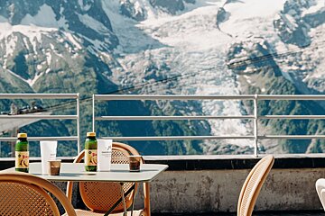 A bottle of aquafina sits on a table with mountains in the background