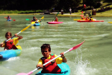 A group of kids are paddling kayaks on a lake