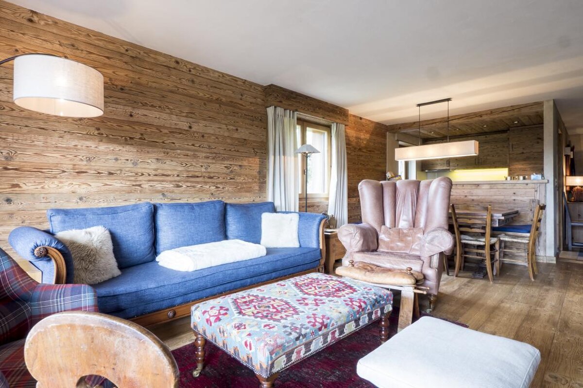 A living room with a blue couch and a brown chair
