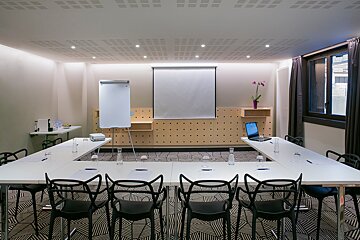 A conference room with tables and chairs and a projector screen