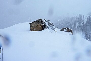 a man skiing near a hut off piste