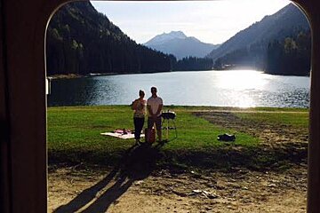 two people stood by a BBQ at a lake near morzine