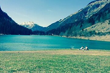 two people sat on the edge of the lake in montriond near morzine
