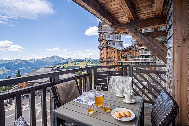 A balcony with a table and chairs with a view of the mountains