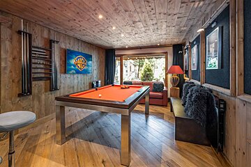 A pool table in a room with a wb logo on the wall