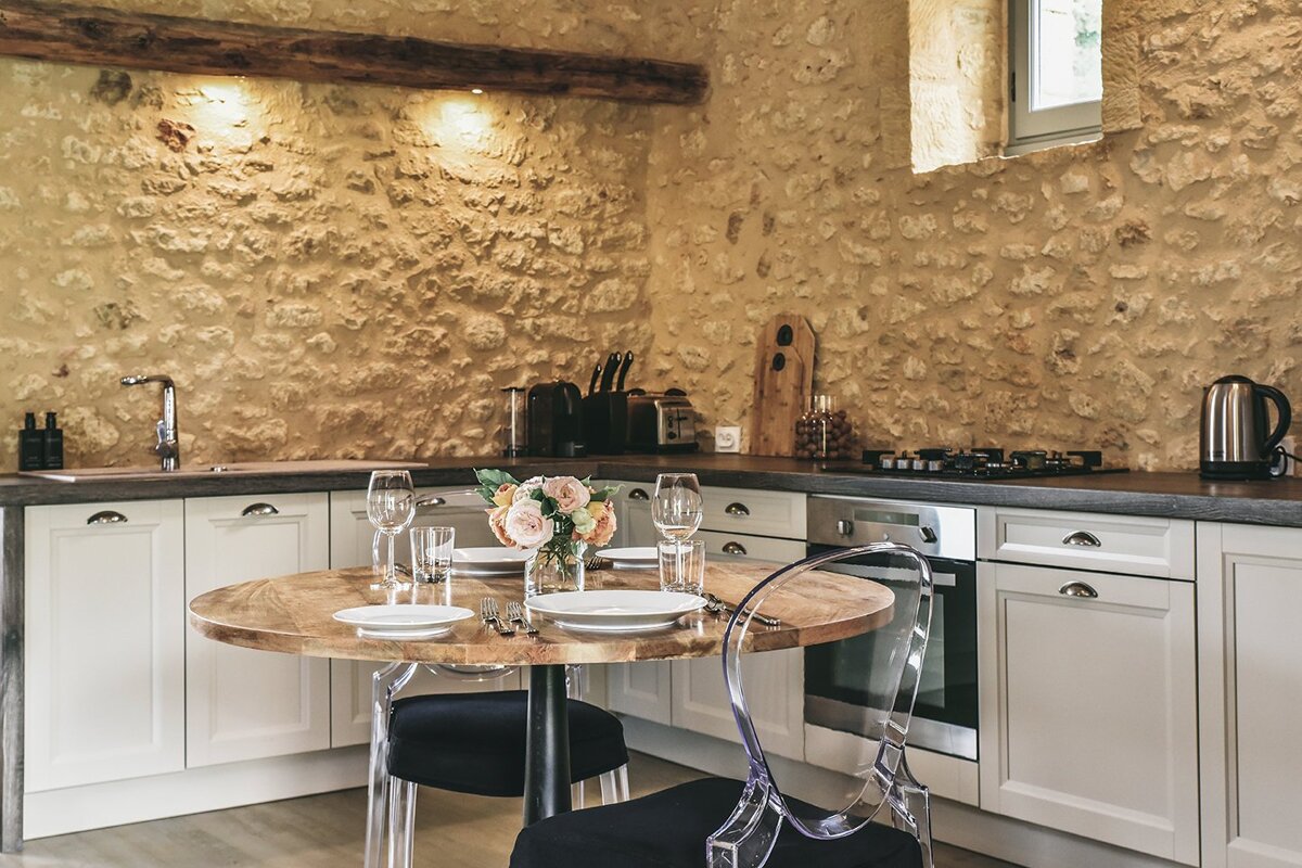 A kitchen with a round table and clear chairs