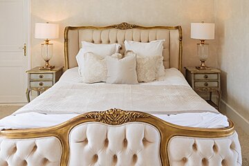 A bed with a gold headboard and white sheets