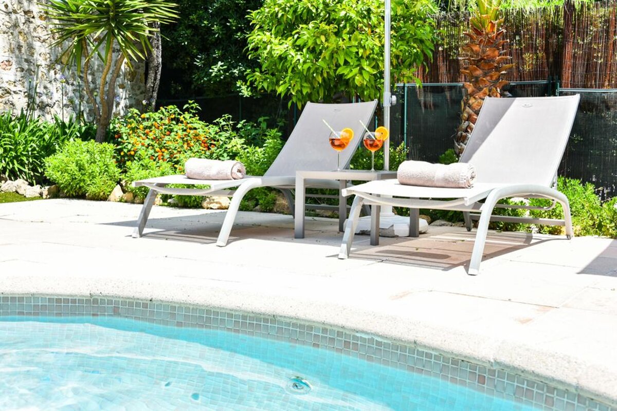 A swimming pool with two lounge chairs with drinks on them