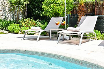 A swimming pool with two lounge chairs with drinks on them