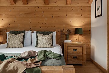 A bedroom with a bed and a nightstand with a lamp on it