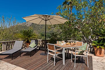 A wooden deck with a table and chairs under an umbrella