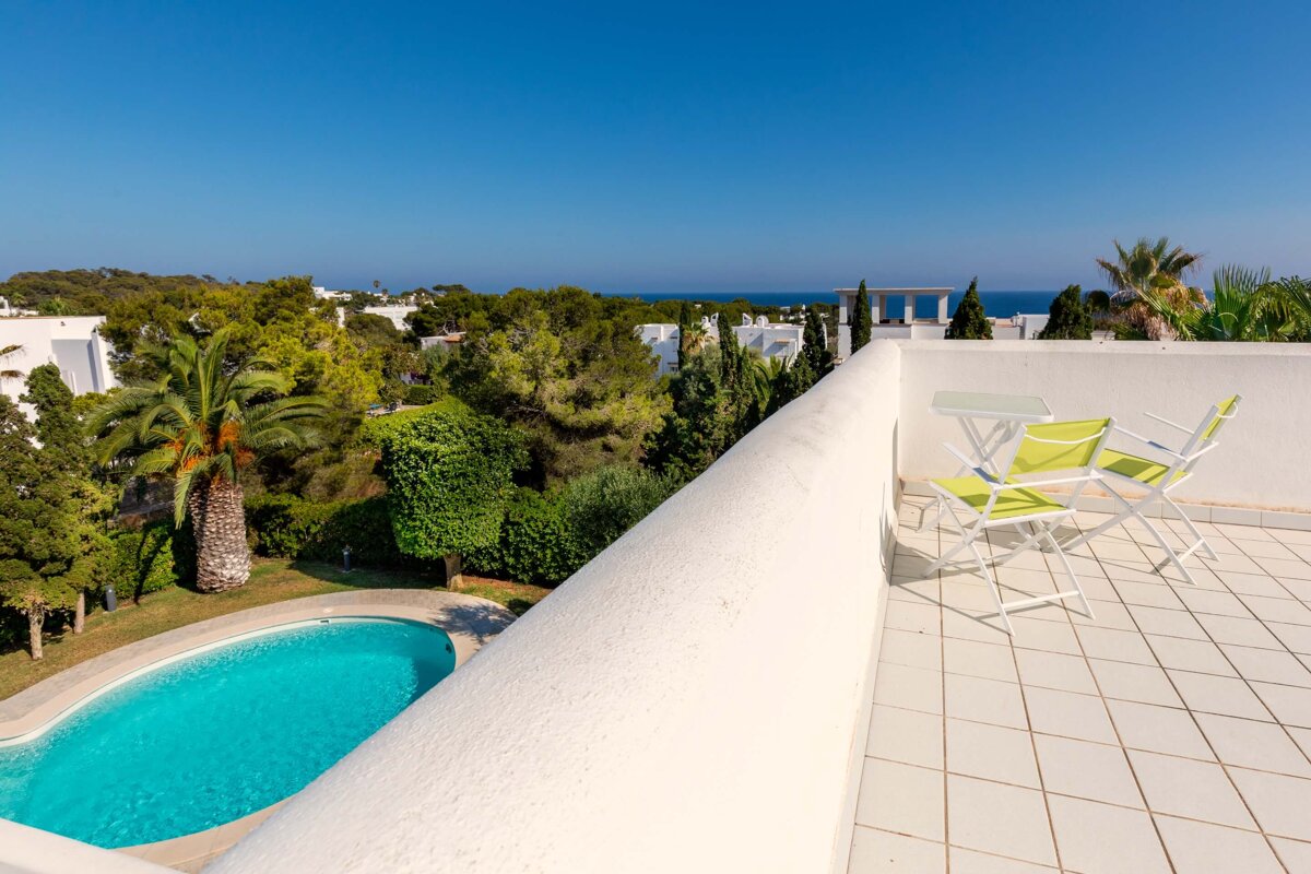 A balcony with a table and chairs overlooking a swimming pool