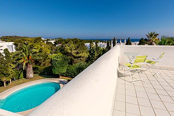 A balcony with a table and chairs overlooking a swimming pool