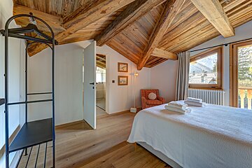 A bedroom with a wooden ceiling and a bed