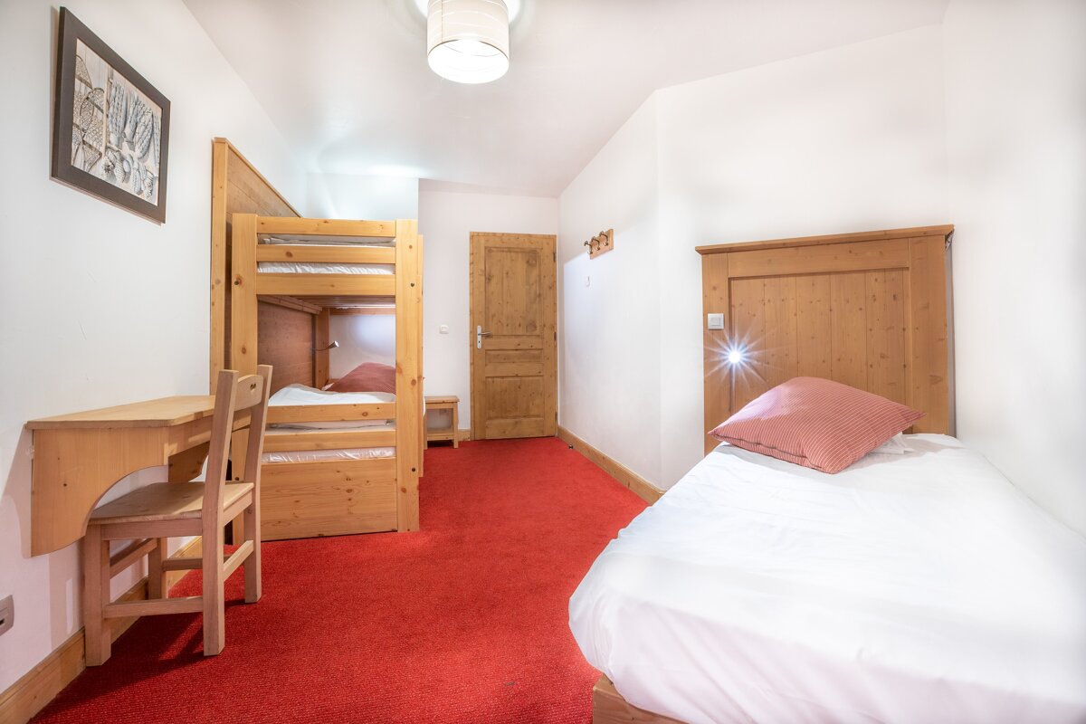 A bedroom with two bunk beds and a desk