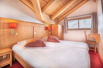 A bedroom with two beds and a window with mountains in the background