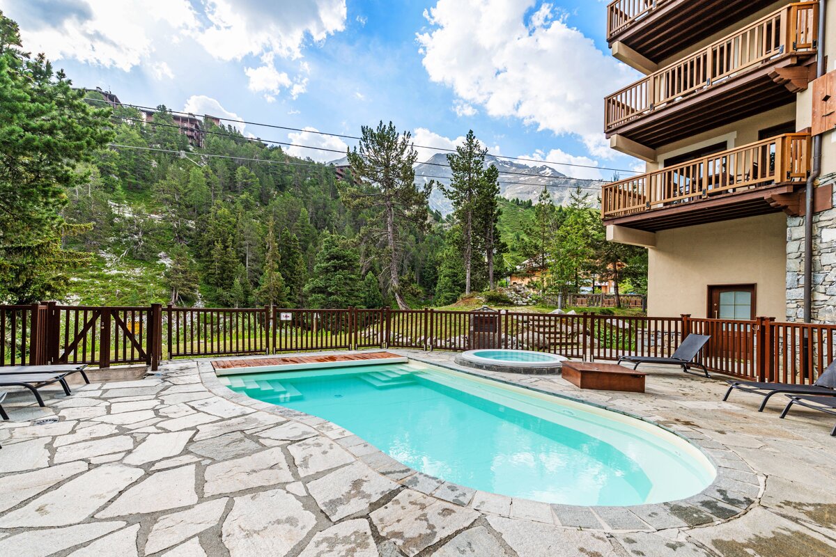 A large swimming pool in front of a building with a mountain in the background