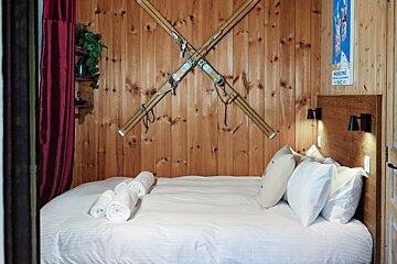 A bedroom with skis on the wall and a poster that says marlene